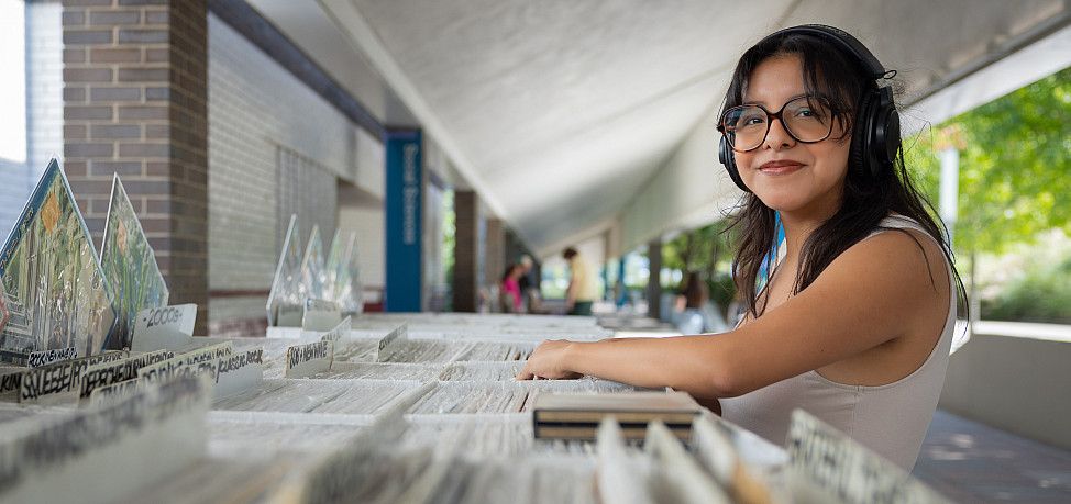 Student smiles while flipping through bins of vinyl LPs