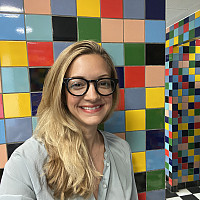 Professor Hilary Whitham Sánchez smiling in front of colorful wall art.