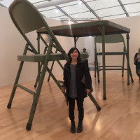 Graduate Student Noriko Okada standing next to a large table and chair.