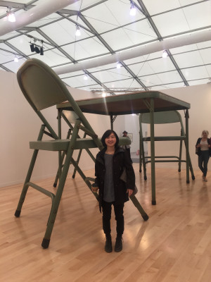 Graduate Student Noriko Okada standing next to a large table and chair.