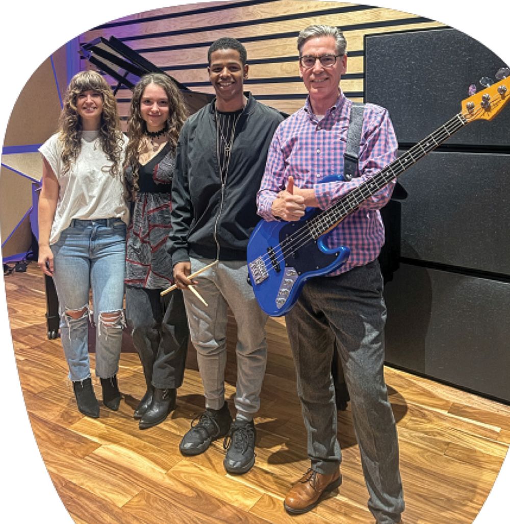 Assistant Professor Rebecca Haviland, students, and President Steiper holding a guitar