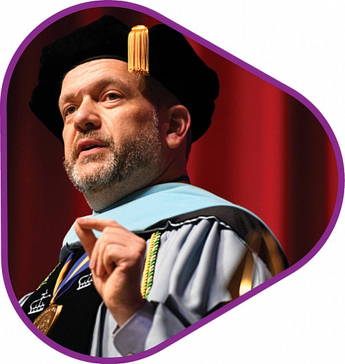 Jeffrey Putman '96 in academic regalia in triangular photo frame with pink outline
