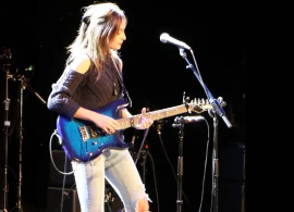 Student on stage with guitar and mic