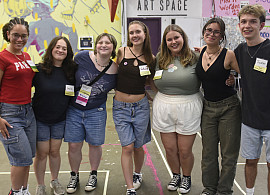 Group of students stands arms around each other.