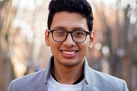 Student in white shirt and grey blazer and glasses.