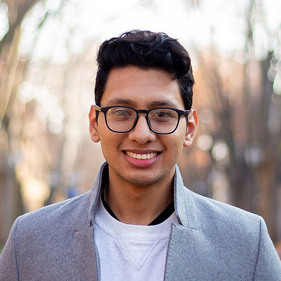 Student in white shirt and grey blazer and glasses.