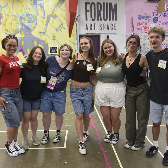Group of students stands arms around each other.