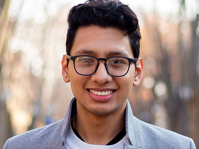 Student in white shirt and grey blazer and glasses.