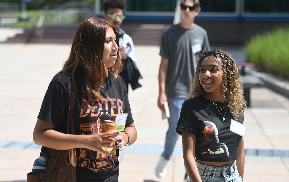 Two students talk while walking on campus