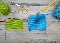 green and blue yarn, crochet and knit needles and a scissor on a table.