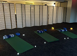 Picture of yoga matts and light candles on the floor with screens behind it in a warmly lit  Harbor Center room.