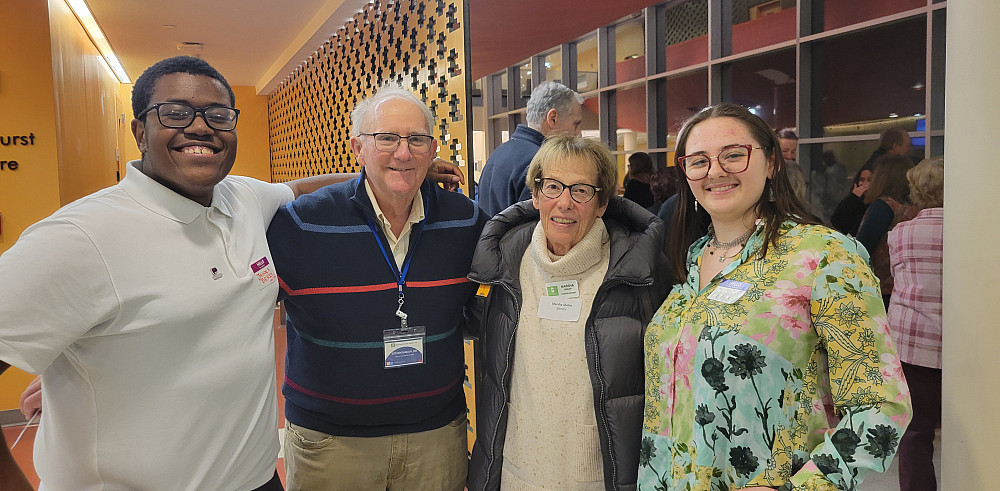 Four students and mentors stand arm-in arm