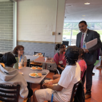 Chancellor King stands at a table chatting with EOP students.