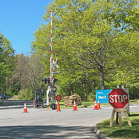 A crossroads with orange cones and a railroad crossing gate.