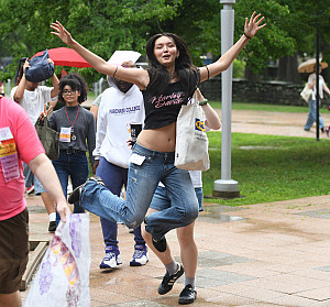 New student in jeans and black cutoff tshirt leaps in the air.