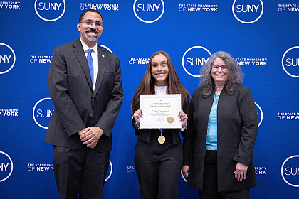 SUNY Chancellor John D. King, Caiityl Dominici '24 holding award certificate, Purchase President Milagros Peña.