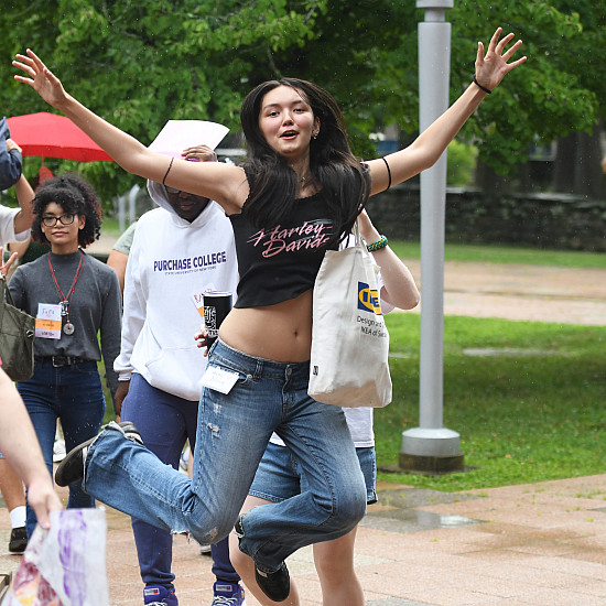 New student in jeans and black cutoff tshirt leaps in the air.