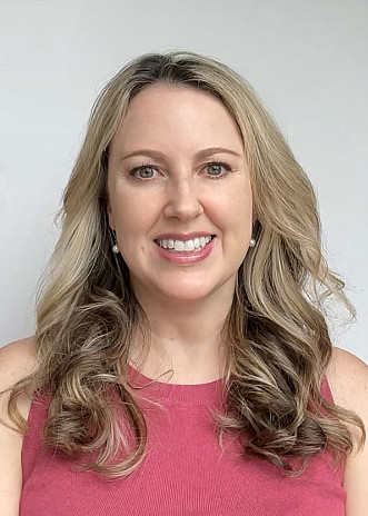 Smiling blonde woman wearing a pink shirt.