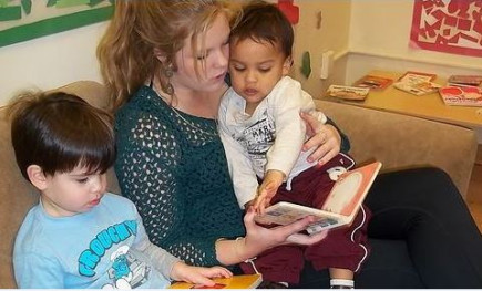 Woman reading a book to two children