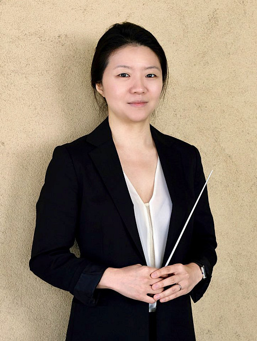 A portrait of Mina Kim, Orchestra Director, with a baton.