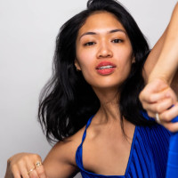 Asian American woman in blue with elbow in the air