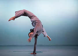 Dancer in motion, mid-handstand while extending legs.