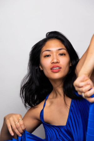 Asian American woman in blue with elbow in the air