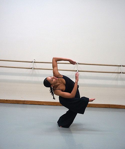 Dancer Bianca Calá in dance position twist with legs bent and eyes looking up.