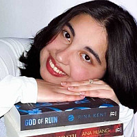 Student Paola Anguiano laying her head on a stack of books