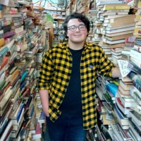 Student Thomas Sclafani standing in between two rows of filled book shelves