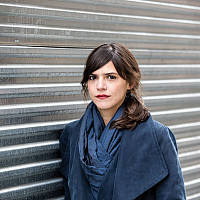 Author Valeria Luiselli standing in front of gray wall