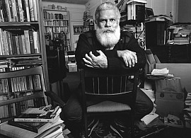 Author Samuel R. Delany sitting in a chair with a background of books