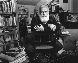Author Samuel R. Delany sitting in a chair with a background of books