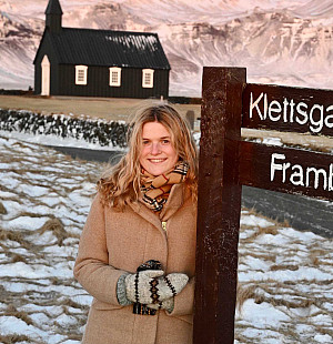 Student Rose McCoy standing next to a wooden post with a house in the background