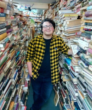 Student Thomas Sclafani standing in between two rows of filled book shelves