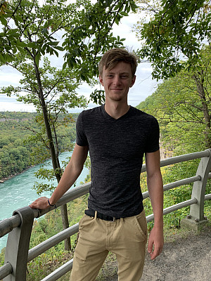 Student Peter Moriarty standing in front of wooden fence with river in background