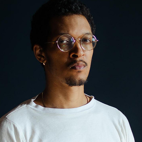 Caleb Eberhardt '12 sits in a chair against dark background.