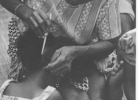 Ma Kpanna dressing hair of Simo Bolay at the entrance into Sande Bush, Bandi, Bolahun, Liberia. Photograph by William Sieggman, 1981