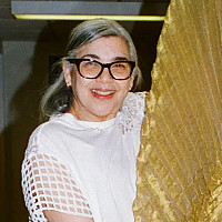 Suzi-Gomez-Pizzo holds up a gold gown costume.