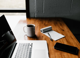 Laptop, smart phone, coffee cup and notepad on wooden table