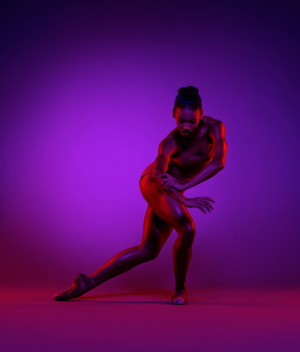 Raven Barkley '15 / Photo: Todd Rosenberg, Courtesy Charlotte Ballet (Barkley holds a dance pose bathed in purple light.)