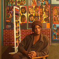 Artist sits in a chair surrounded by brightly colored narrative paintings