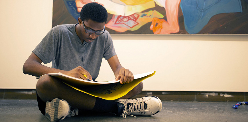 Student sits on the floor drawing.