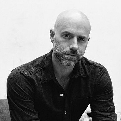 Black and white photo of Dan Romer '04 sitting in a chair