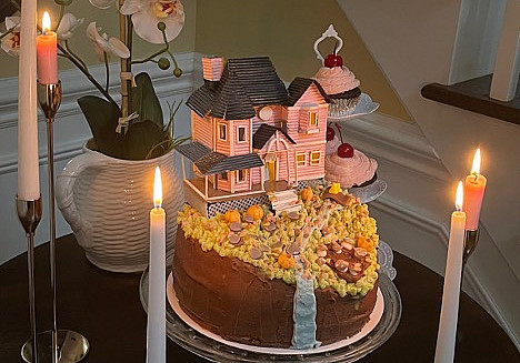 Whimsical cake on a stand surrounded by taper candles