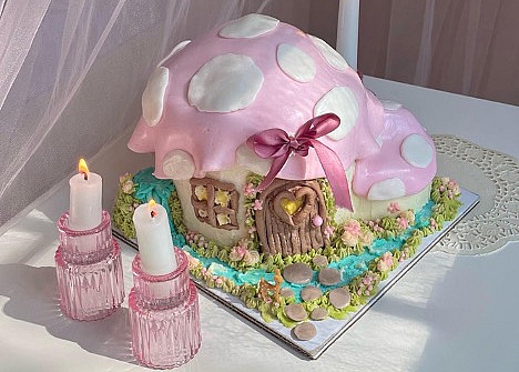 Whimsical cake on a stand surrounded by taper candles