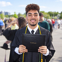 SUNY Purchase alum Daniel Muñoz '26 holds his diploma at commencement.