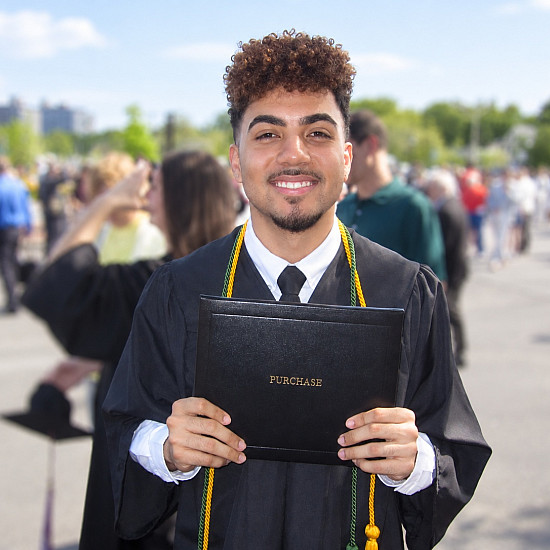 SUNY Purchase alum Daniel Muñoz '26 holds his diploma at commencement.