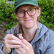 Dr. Allyson Jackson holding a bird during field work