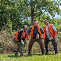    Corey standing in front of a pile of removed invasives 